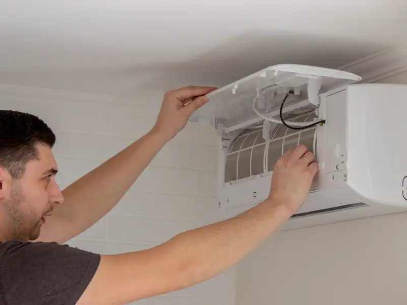 Démontage du capot d'une unité murale par un technicien avant son nettoyage