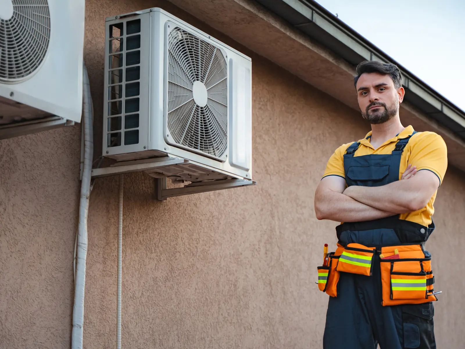 Dépanneur devant un groupe extérieur de climatisation dans un jardin arboré
