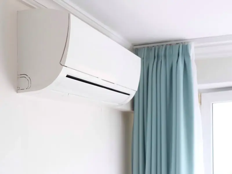 Climatiseur mural installé en haut du mur d'une chambre