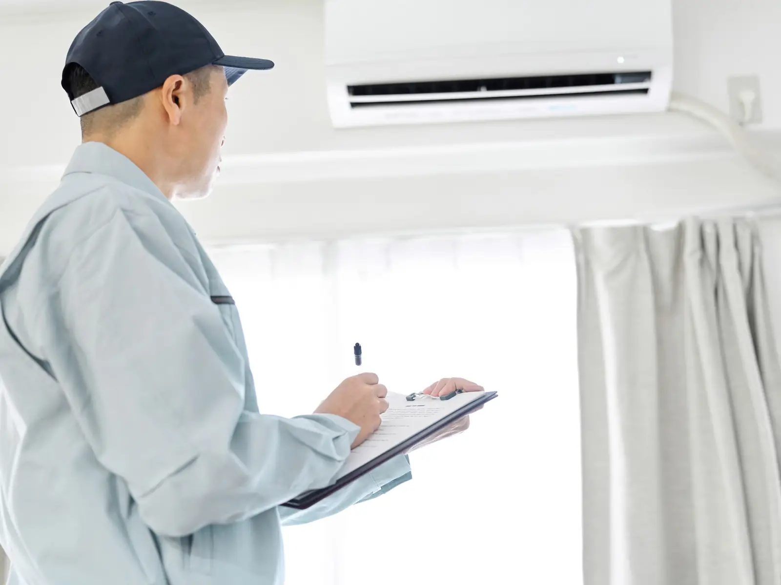 Technicien consignant le relevé des contrôles d'entretien d'une climatisation