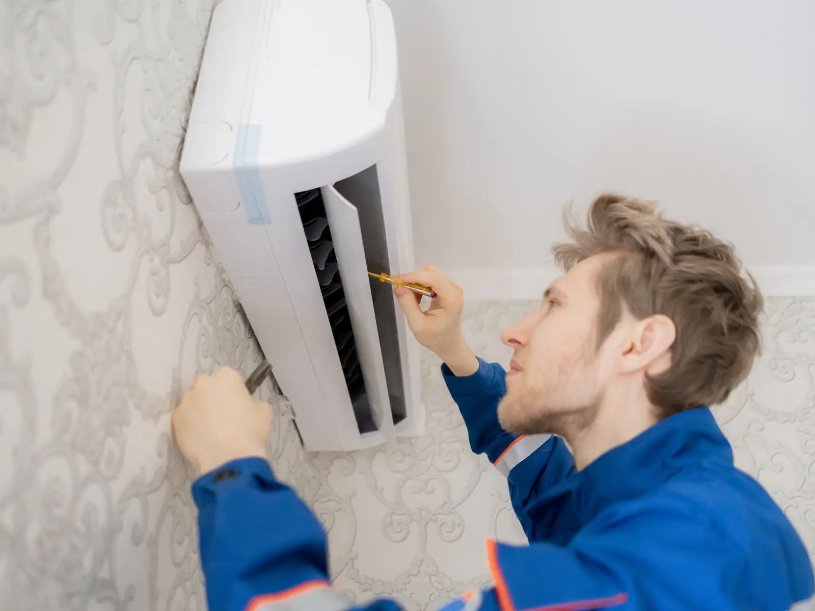 Technicien inspectant un climatiseur mural à la recherche de l'origine d'un bruit