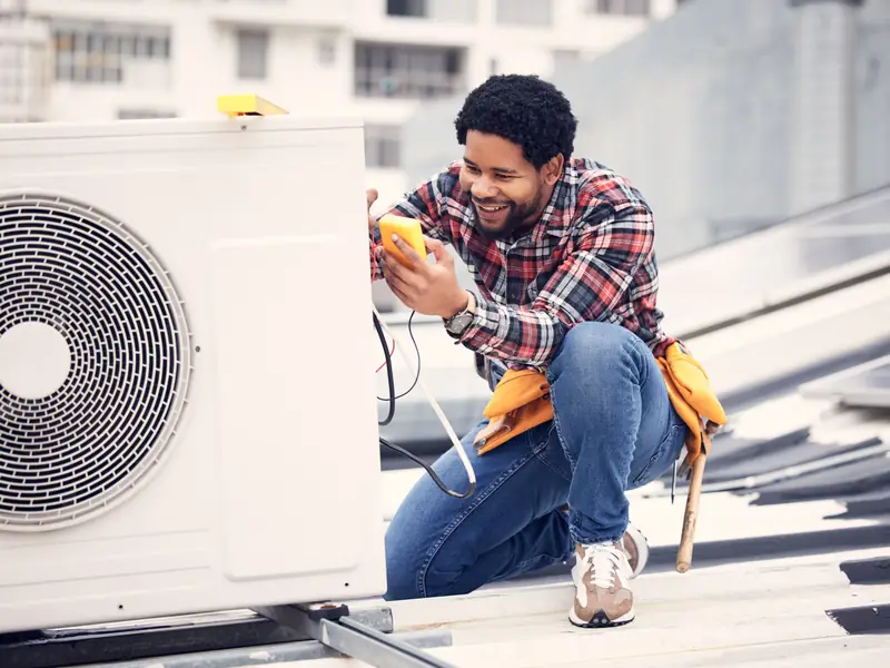 Technicien réalisant des mesures électriques sur un groupe extérieur de climatisation