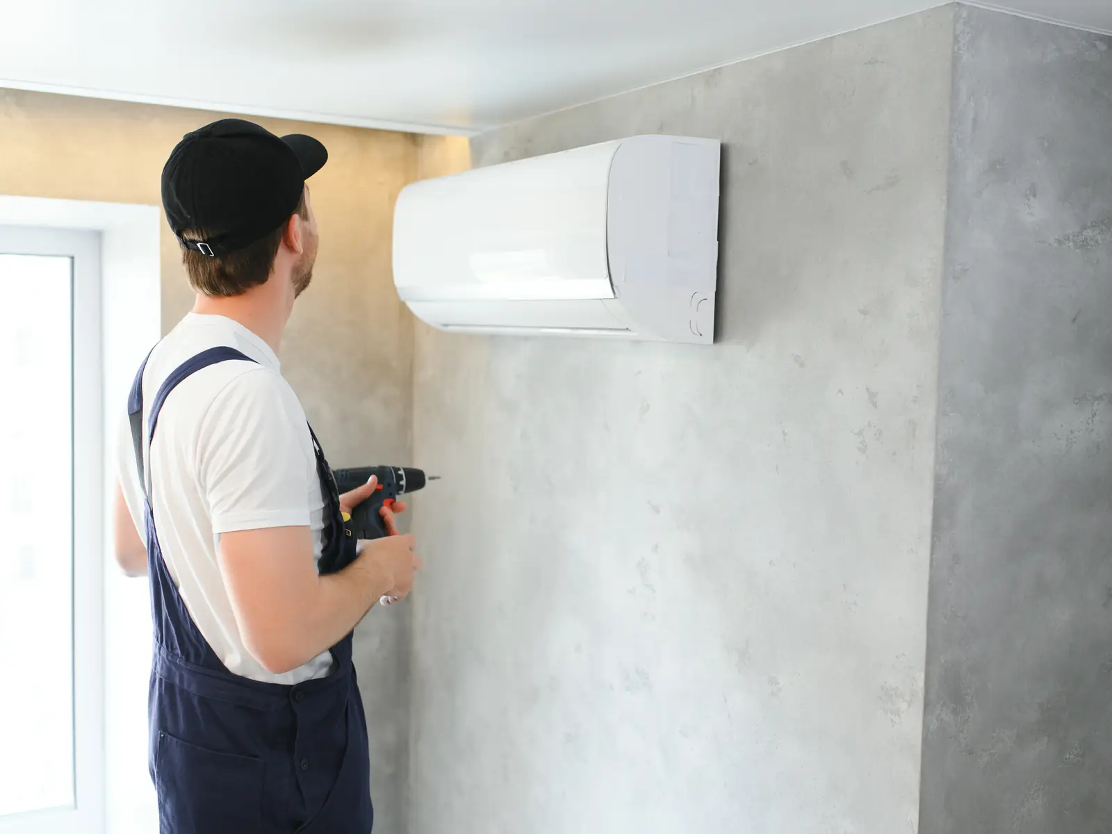 Technicien en train de poser une unité murale de climatisation dans un logement